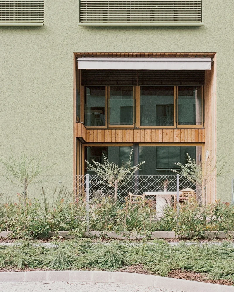 Dvoetažna stanovanjska odprtina z leseno oblogo in ograjenim zunanjim prostorom.